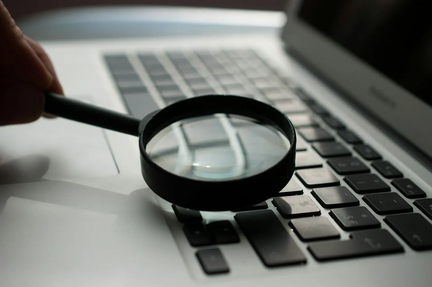 A magnifying glass resting on a laptop keyboard